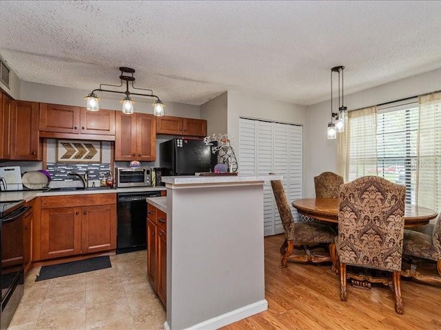 kitchen with decorative light fixtures, black appliances, sink, a kitchen island, and a textured ceiling