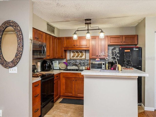 kitchen featuring hanging light fixtures, black appliances, backsplash, light tile floors, and a textured ceiling