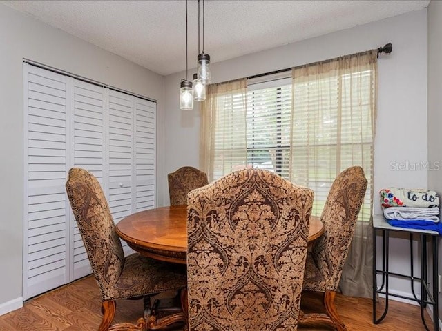 dining space with wood-type flooring and a textured ceiling