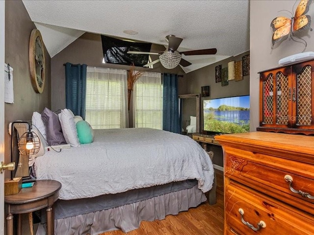 bedroom featuring a textured ceiling, hardwood / wood-style floors, ceiling fan, and lofted ceiling