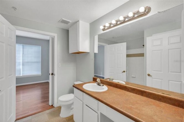 bathroom featuring wood-type flooring, toilet, and oversized vanity