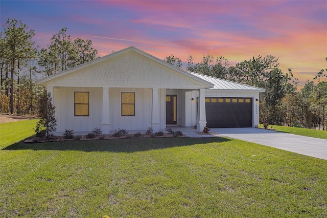 modern farmhouse featuring covered porch, a garage, and a yard