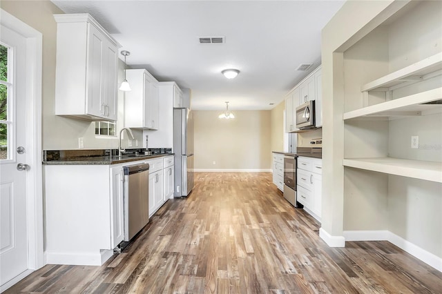 kitchen featuring white cabinetry, dark hardwood / wood-style floors, appliances with stainless steel finishes, and pendant lighting