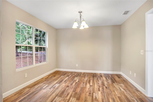 spare room featuring a chandelier and wood-type flooring