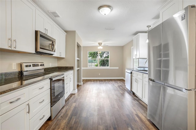 kitchen with appliances with stainless steel finishes, white cabinets, decorative light fixtures, dark hardwood / wood-style floors, and ceiling fan