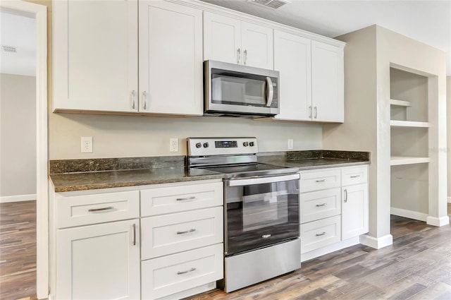 kitchen featuring dark stone counters, white cabinetry, hardwood / wood-style floors, and stainless steel appliances