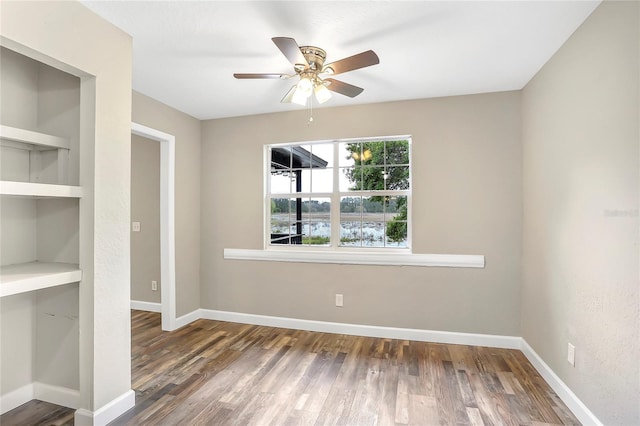 empty room featuring built in shelves, ceiling fan, and hardwood / wood-style floors