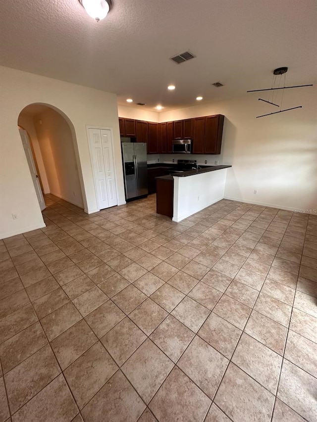 kitchen with a textured ceiling, stainless steel appliances, kitchen peninsula, and light tile floors