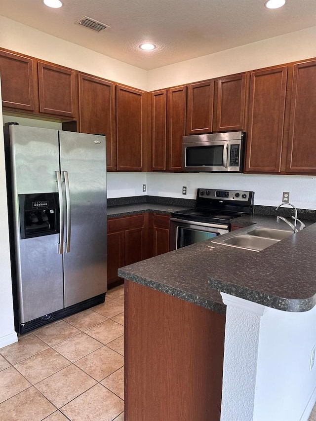 kitchen with sink, kitchen peninsula, light tile floors, and stainless steel appliances