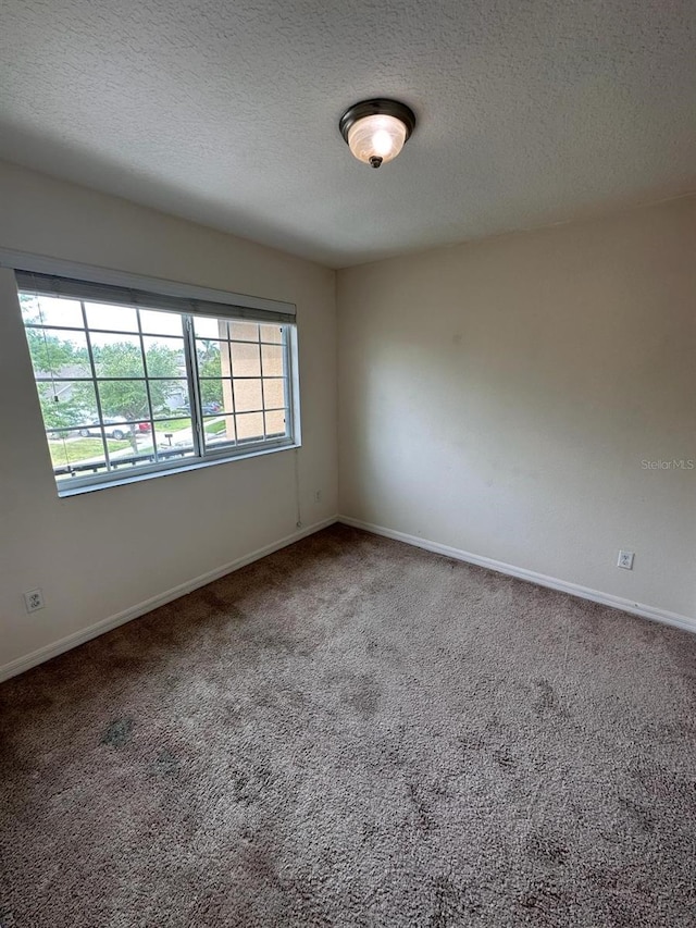 empty room featuring a textured ceiling and carpet flooring