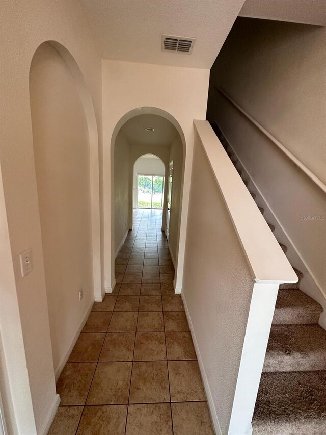 hall featuring a textured ceiling and tile floors