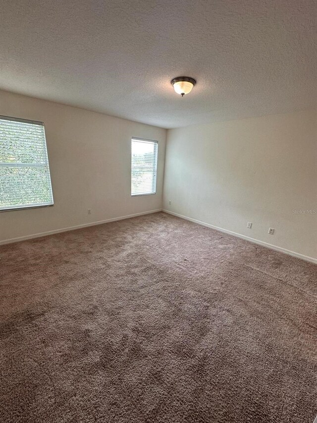 carpeted empty room with a textured ceiling