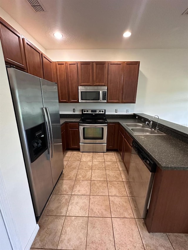 kitchen with sink, stainless steel appliances, kitchen peninsula, and light tile flooring