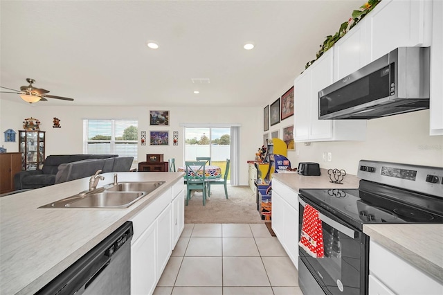 kitchen featuring appliances with stainless steel finishes, sink, light tile flooring, and white cabinetry