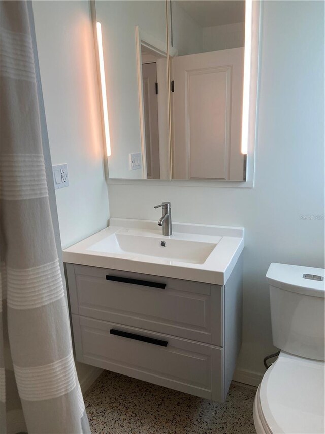 bathroom featuring vanity, toilet, and speckled floor