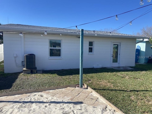 rear view of property featuring a lawn and central AC unit