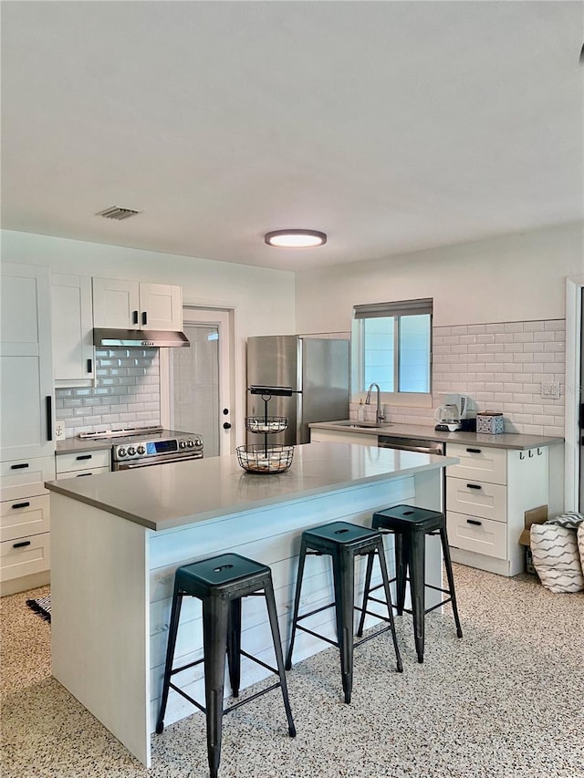 kitchen with visible vents, under cabinet range hood, appliances with stainless steel finishes, white cabinetry, and light speckled floor