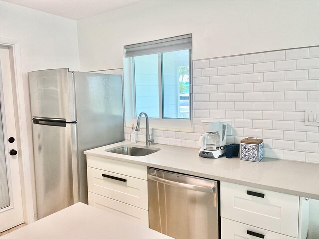 kitchen with appliances with stainless steel finishes, white cabinetry, decorative backsplash, and sink