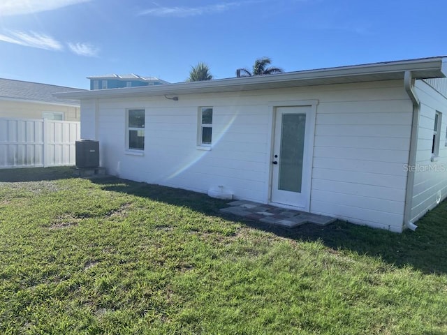 rear view of house featuring a yard, central air condition unit, and fence