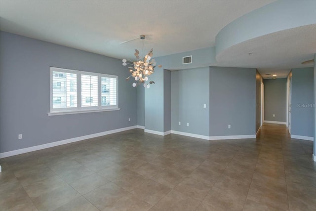 tiled spare room featuring a textured ceiling and a chandelier