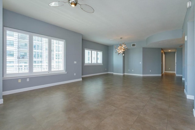 spare room featuring a notable chandelier and tile floors