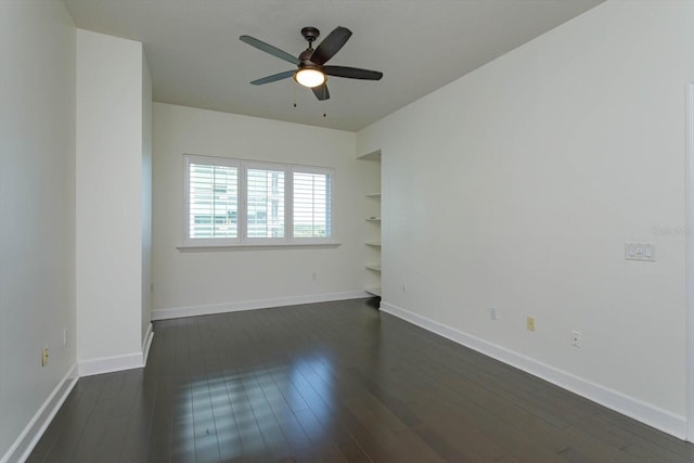 spare room with built in features, dark wood-type flooring, and ceiling fan