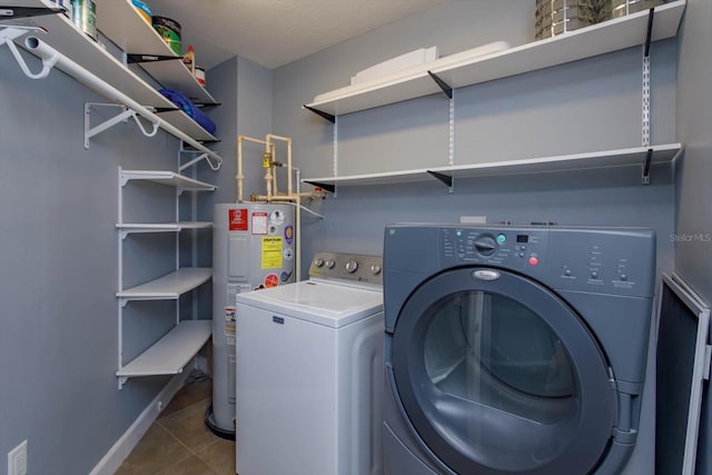 laundry area with tile flooring, water heater, a textured ceiling, and washing machine and clothes dryer