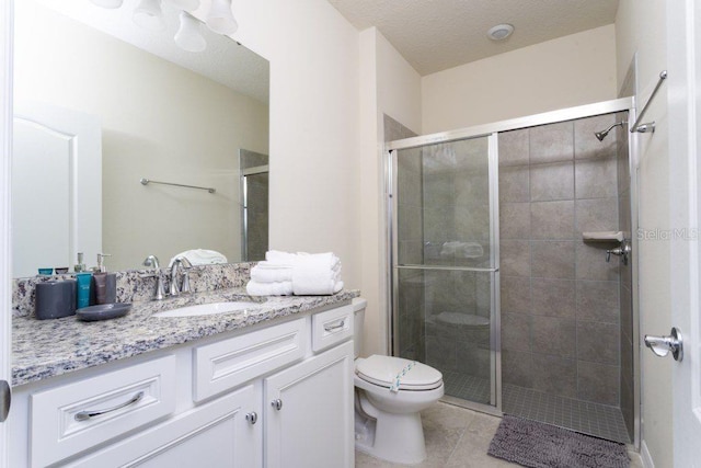 bathroom with vanity with extensive cabinet space, an enclosed shower, toilet, and tile flooring