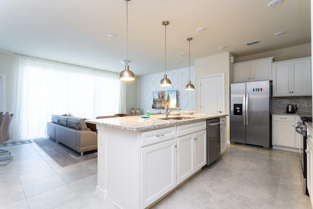 kitchen featuring light stone countertops, stainless steel appliances, an island with sink, white cabinets, and sink