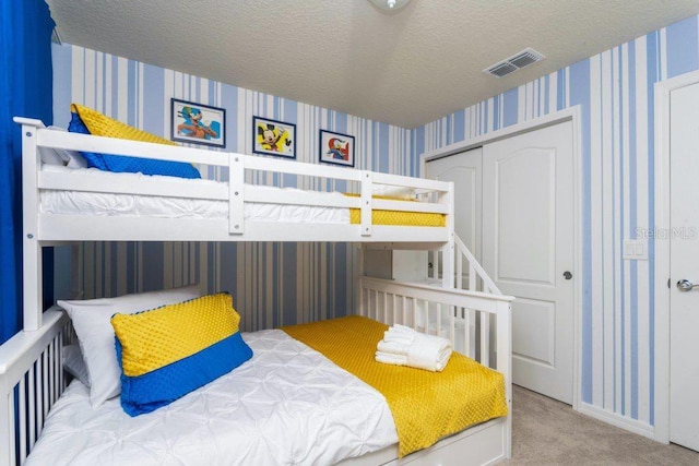 bedroom featuring light carpet, a closet, and a textured ceiling