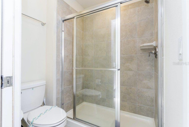 bathroom with a shower with shower door and toilet