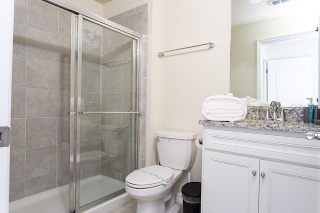 bathroom featuring a shower with door, vanity, and toilet