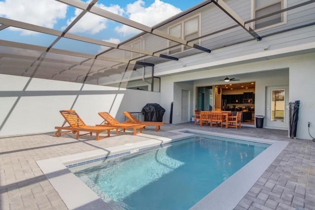 view of swimming pool featuring glass enclosure, ceiling fan, and a patio area