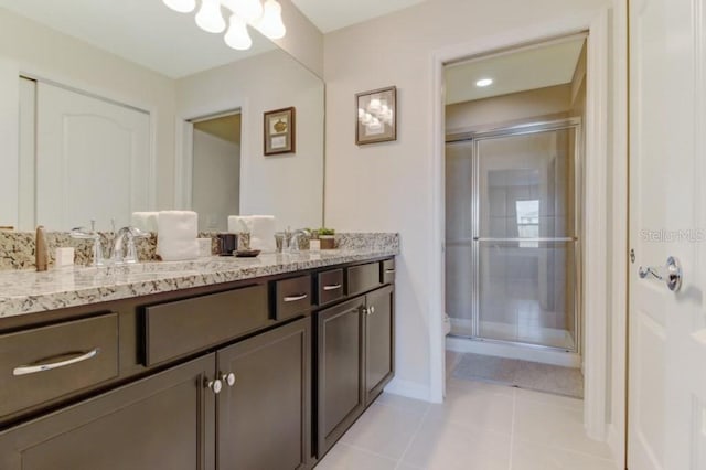 bathroom featuring dual sinks, oversized vanity, tile floors, and a shower with shower door