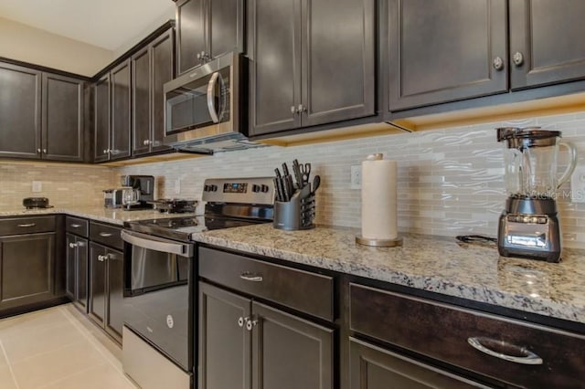 kitchen featuring light tile flooring, backsplash, range with electric cooktop, and light stone counters