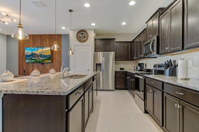 kitchen with decorative light fixtures, backsplash, stainless steel appliances, light stone counters, and light tile floors