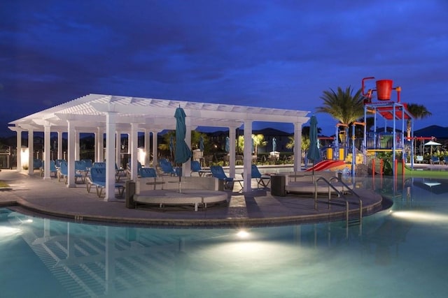 pool at night with a pergola and a patio area