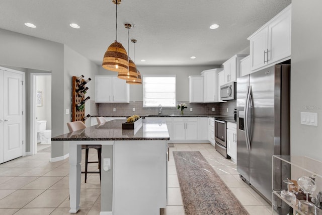 kitchen featuring sink, stainless steel appliances, pendant lighting, a breakfast bar, and a kitchen island