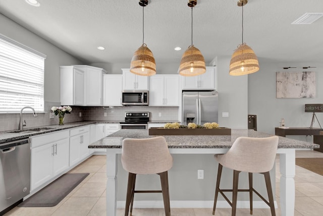 kitchen with pendant lighting, a kitchen island, sink, and stainless steel appliances