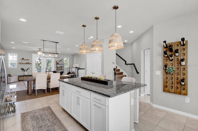 kitchen featuring pendant lighting, a center island, white cabinetry, and dark stone counters