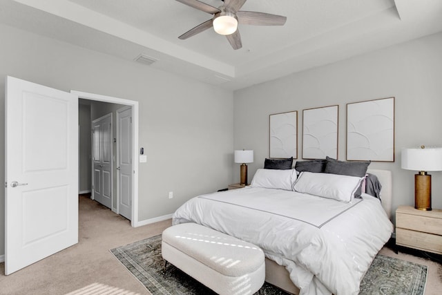 carpeted bedroom featuring a tray ceiling and ceiling fan