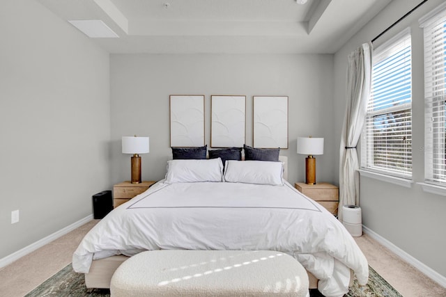 carpeted bedroom with a tray ceiling and multiple windows