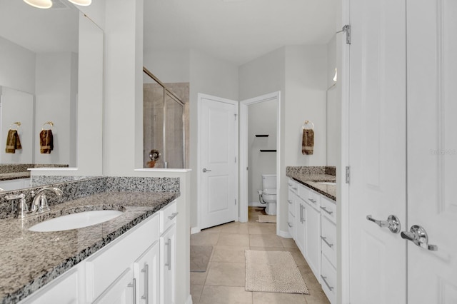 bathroom with toilet, vanity, tile patterned floors, and a shower with door