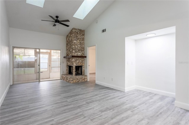 unfurnished living room featuring ceiling fan, a stone fireplace, light wood-type flooring, and high vaulted ceiling