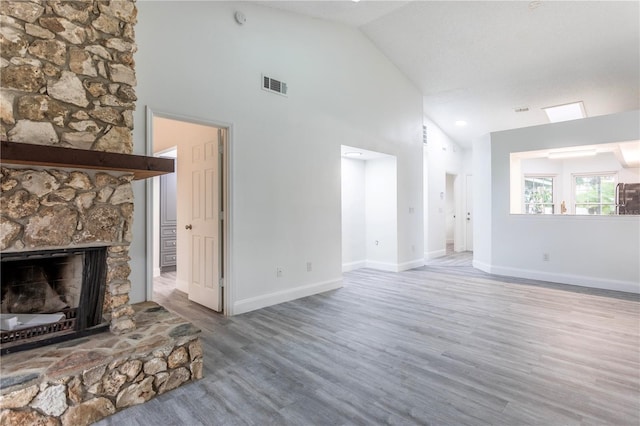 unfurnished living room with a textured ceiling, wood-type flooring, a fireplace, and high vaulted ceiling