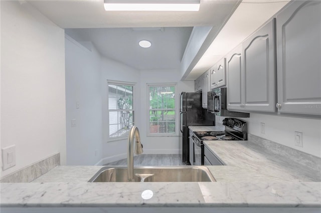 kitchen featuring light stone counters, sink, black appliances, and hardwood / wood-style flooring