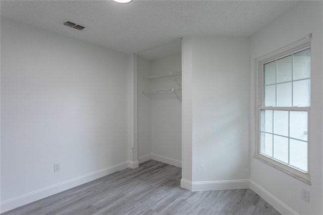 unfurnished bedroom featuring a closet, a textured ceiling, and light hardwood / wood-style flooring