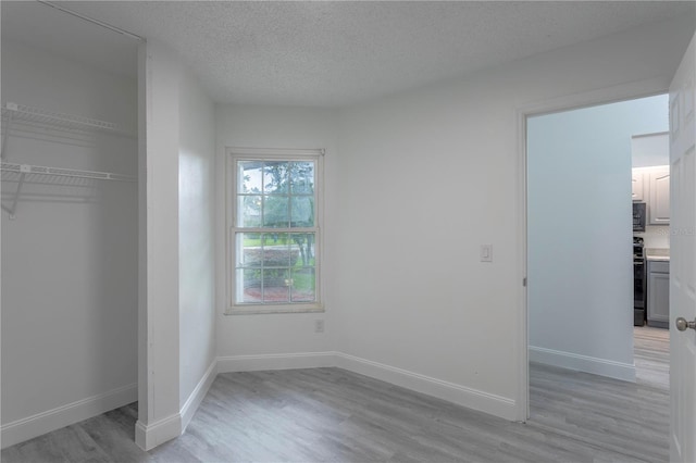 unfurnished bedroom with a closet, light hardwood / wood-style flooring, and a textured ceiling