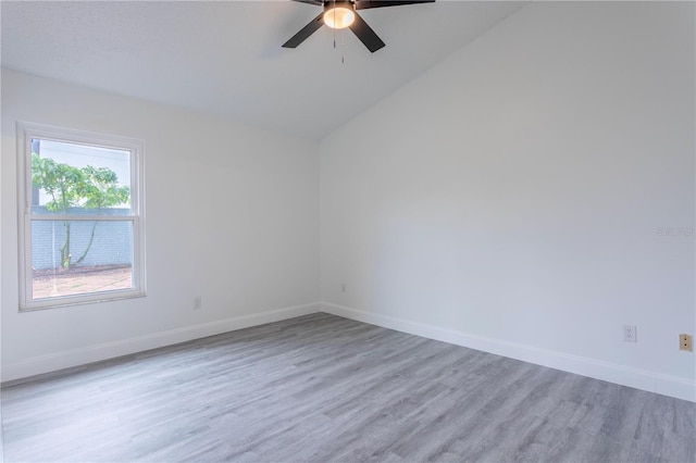 spare room featuring ceiling fan, lofted ceiling, and light wood-type flooring