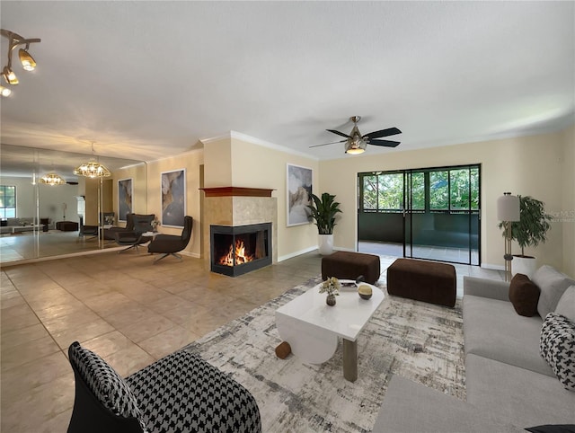 living room with ornamental molding, light tile patterned flooring, ceiling fan with notable chandelier, and a fireplace